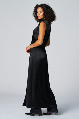 Robe sans manches noire d'Astrid Black Label, avec une fente latérale et portée avec des bottes noires à strass.