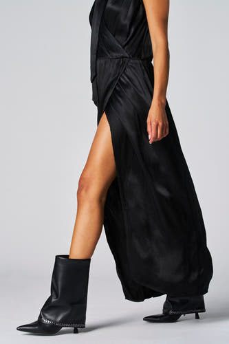 Zwarte mouwloze kleedje van Astrid Black Label, met een zijsplit en gedragen met zwarte laarsjes met studs.
