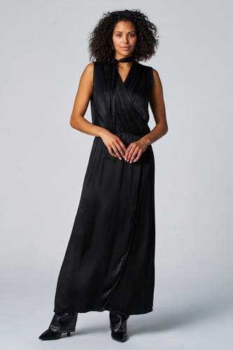 Robe sans manches noire d'Astrid Black Label, avec un col plié et une jupe trapèze, portée avec des escarpins noirs.