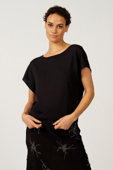 Zwarte trui met ronde hals van Astrid Black Label, met korte mouwen en een rok met decoratieve details.
