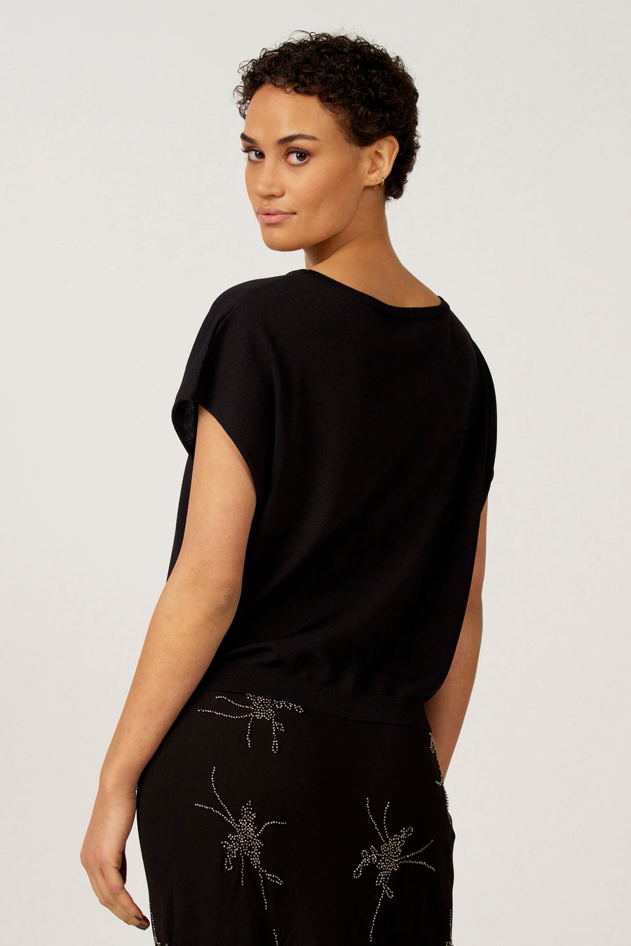 Vrouw in zwarte top en rok met zilveren details.