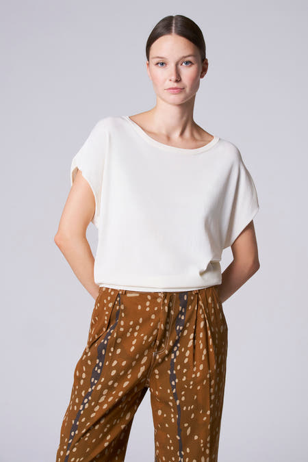 T-shirt écru avec col rond d'Astrid Black Label, manches courtes et associé à un pantalon marron à carreaux.