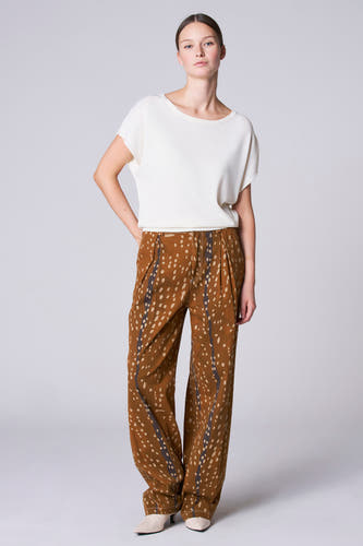 Tunique écru avec col rond d'Astrid Black Label, associée à un pantalon marron-beige à carreaux et des talons hauts.