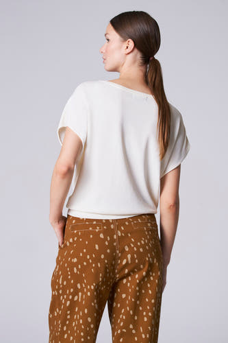 Ecru trui met ronde hals van Astrid Black Label, met korte mouwen en gecombineerd met een bruine broek met stippen.
