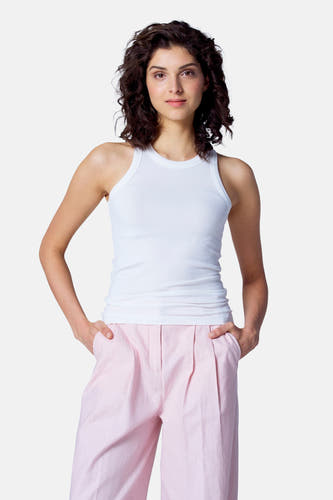 T-shirt blanc d'Astrid Black Label, vu de derrière, avec un short rose et des cheveux bouclés foncés.