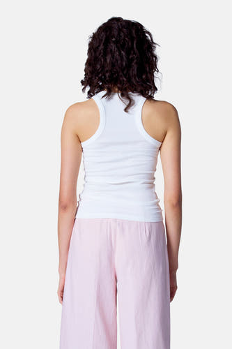 Witte singlet van Astrid Black Label, achterkant gezien, met roze broek en donkere krullen.
