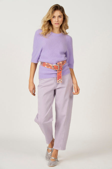 Vrouw draagt paarse trui, paarse broek, decoratieve riem en zilveren schoenen.