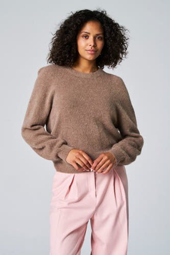 Veste taupe avec col rond d'Astrid Black Label, en tissu doux et portée avec un pantalon rose.