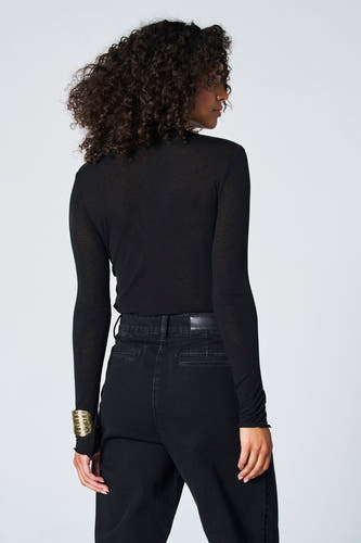 T-shirt noir à manches longues d'Astrid Black Label, porté avec un bracelet en or et des jeans noirs.