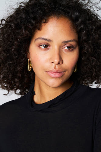 T-shirt noir à manches longues d'Astrid Black Label, porté avec des boucles d'oreilles en or.