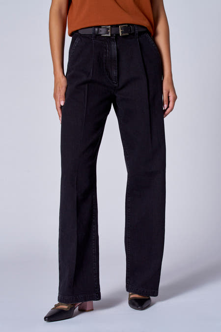Jean wide noir Astrid Black Black, avec des pliées et un porté avec une ceinture noire, une chemise marron et des chaussures noires.