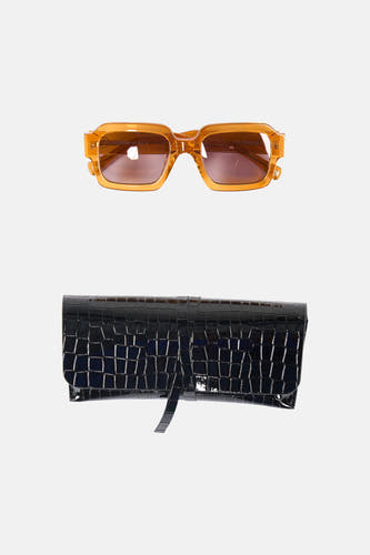 Lunettes de soleil orange d'Astrid Black Label, avec un étui à lunettes noir à motif crocodile.