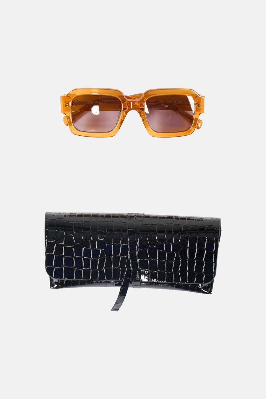 Lunettes de soleil orange d'Astrid Black Label, avec un étui à lunettes noir à motif crocodile.
