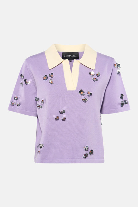 Polo en tricot violet à manches courtes Astrid Black Label, avec col de couleur crème, encolure en V et paillettes argentées en forme de fleur.