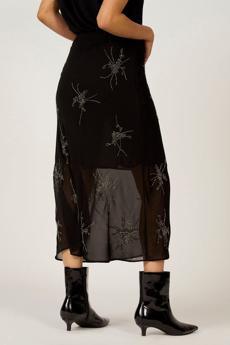 Zwarte rok met zilveren applicaties en zwarte lakleren laarsjes.
