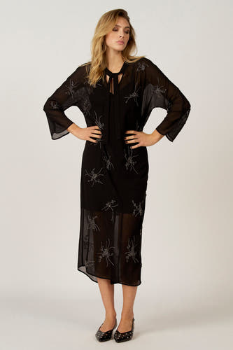 Robe noire avec des manches longues d'Astrid Black Label, ornée de détails argentés et d'une matière transparente.