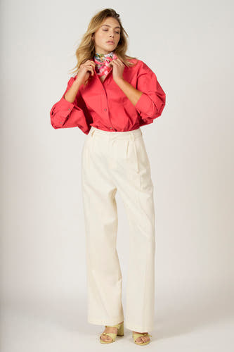 Chemise rose à longues manches d'Astrid Black Label, avec un foulard et associée à un pantalon blanc.