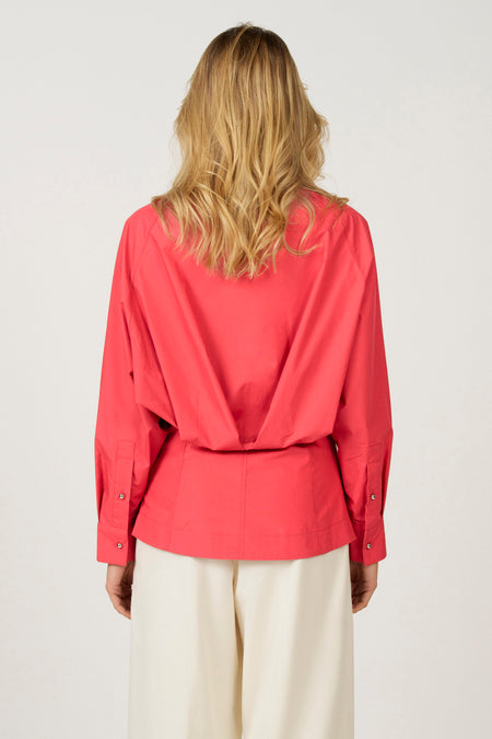 Rode blouse en witte broek van achteren gezien.
