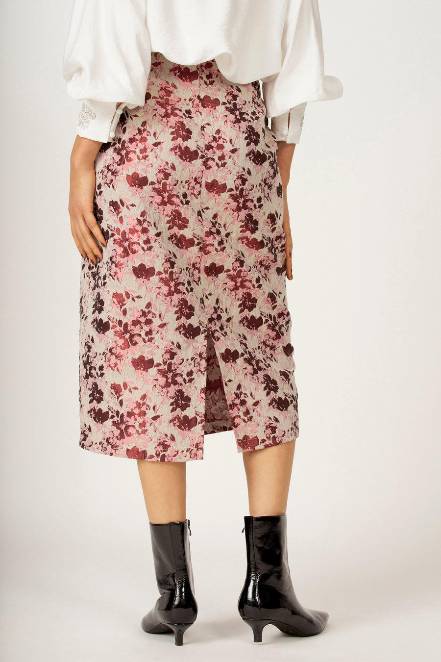 Robe rose Astrid Black Label à motif floral et fendue dans le dos, associée à des bottines noires et une blouse blanche.