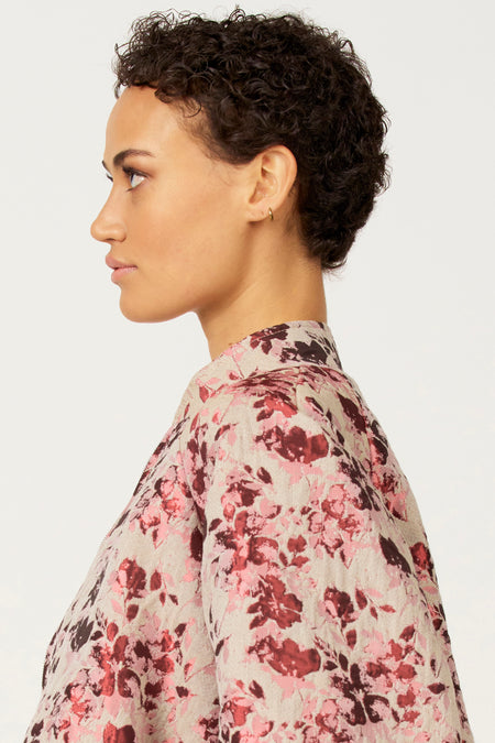 Zijaanzicht van een vrouw met korte krullen in een bloemenblouse.
