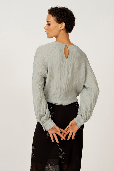 Model in blouse en rok van achteren.