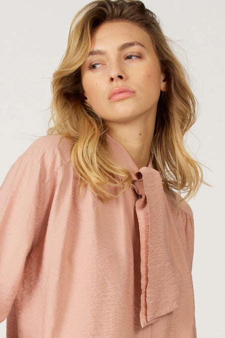 Vrouw in roze blouse met strik.