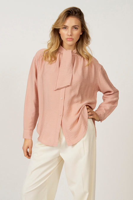 Vrouw met roze blouse en witte broek.