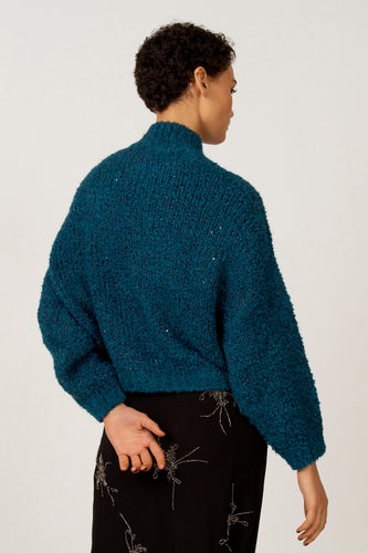 Donkerblauwe trui met pailletten, gecombineerd met een zwarte rok met sierlijke details.