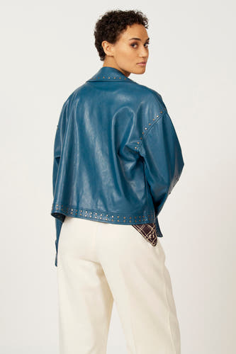 Blauw leren jas van Astrid Black Label, met studs, gecombineerd met een witte broek.