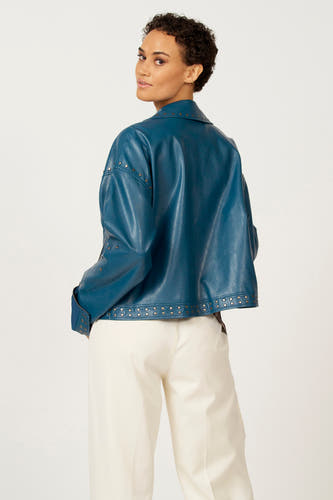 Manteau de cuir bleu d'Astrid Black Label, avec des strass argentés, porté avec un pantalon crème, vue arrière.