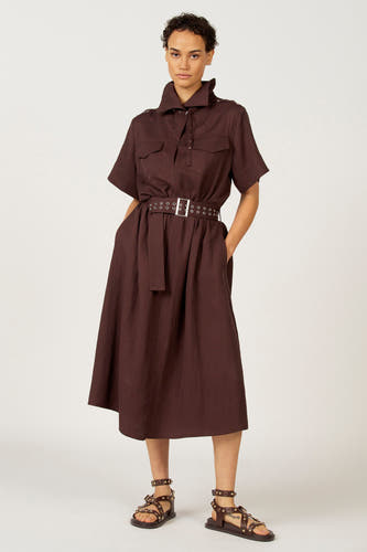 Robe brune à manches courtes d'Astrid Black Label, avec une ceinture en anneaux argentés et des sandales en cuir.
