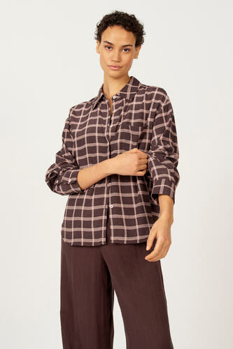 Blouse brune à longues manches d'Astrid Black Label, avec un motif de carreaux roses, portée avec une jupe brune.