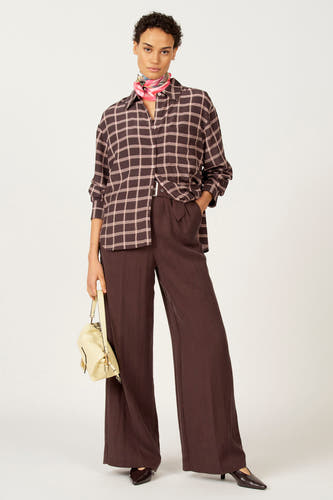 Blouse brune à longues manches d'Astrid Black Label, avec un motif de carreaux et une écharpe en soie autour du cou.
