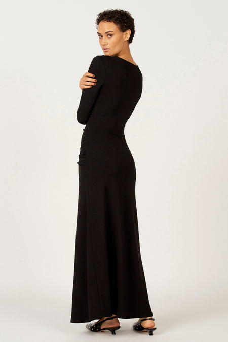 Vrouw in zwarte lange jurk, over de schouder kijkend.