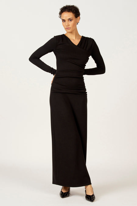 Vrouw in zwarte lange jurk, staand.