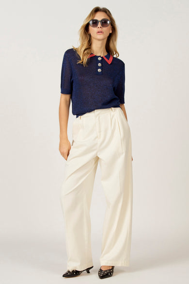 T-shirt bleu à manches courtes d'Astrid Black Label, avec une collet et des boutons décorés décorésééé pant pantalon blanc et des chaussures noires.