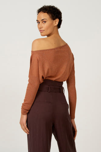 Oranje offshoulder trui van Astrid Black Label, met lange mouwen en gecombineerd met bruine pantalon.
