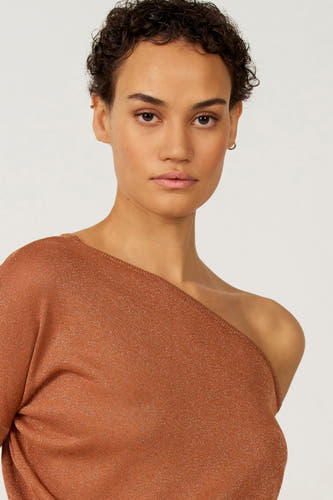 Sweat-shirt à épaules dégagées Oranje d'Astrid Black Label, avec une texture brillante et porté par un modèle aux cheveux courts.