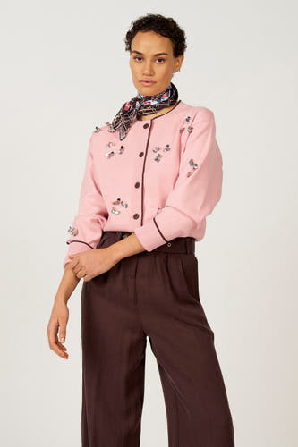 Gilet rose d'Astrid Black Label, avec des fleurs décoratives sur le manche et un pantalon marron.
