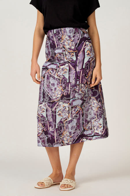 Multikleurige rok van Astrid Black Label, met een abstract bloemenpatroon en gedragen met beige sandalen en een zwart shirt.
