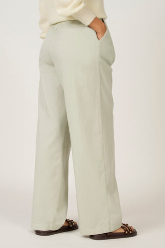 Pantalon vert de Astrid Black Label, avec poche et larges jambes, porté avec un pull tricoté et des sandales.