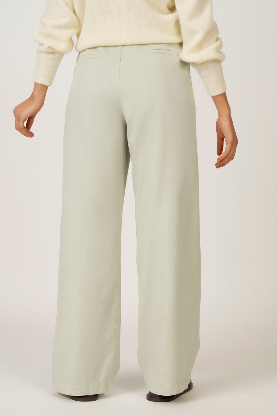 Pantalon vert de Astrid Black Label, vu de l'arrière, associé à une chemise écru.
