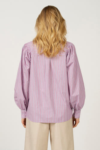 Roze overhemd met lange mouwen van Astrid Black Label, met een gestreept patroon en pofmouwen, op een beige broek.
