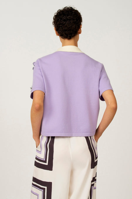 Paarse polo met korte mouwen van Astrid Black Label, met witte kraag en grafische print op de broek.
