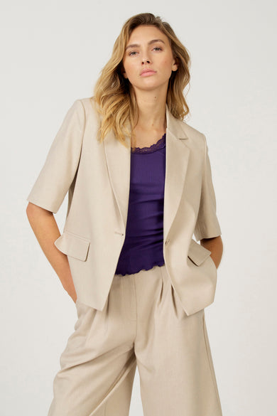 Blazer écru d'Astrid Black Label, vu de dos avec des manches courtes et un pantalon coordonné.