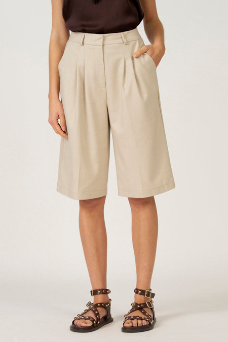 Beige culottes, bruine leren sandalen.
