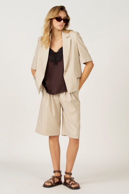 Vrouw in beige pak en bruine sandalen.