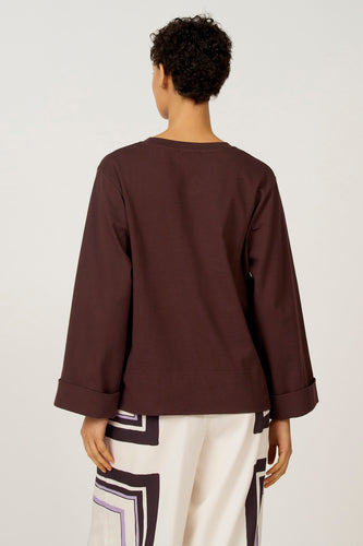 Bruin T-shirt met lange mouwen van Astrid Black Label, met omgeslagen mouwen, gecombineerd met een wit-zwart patroon broek.