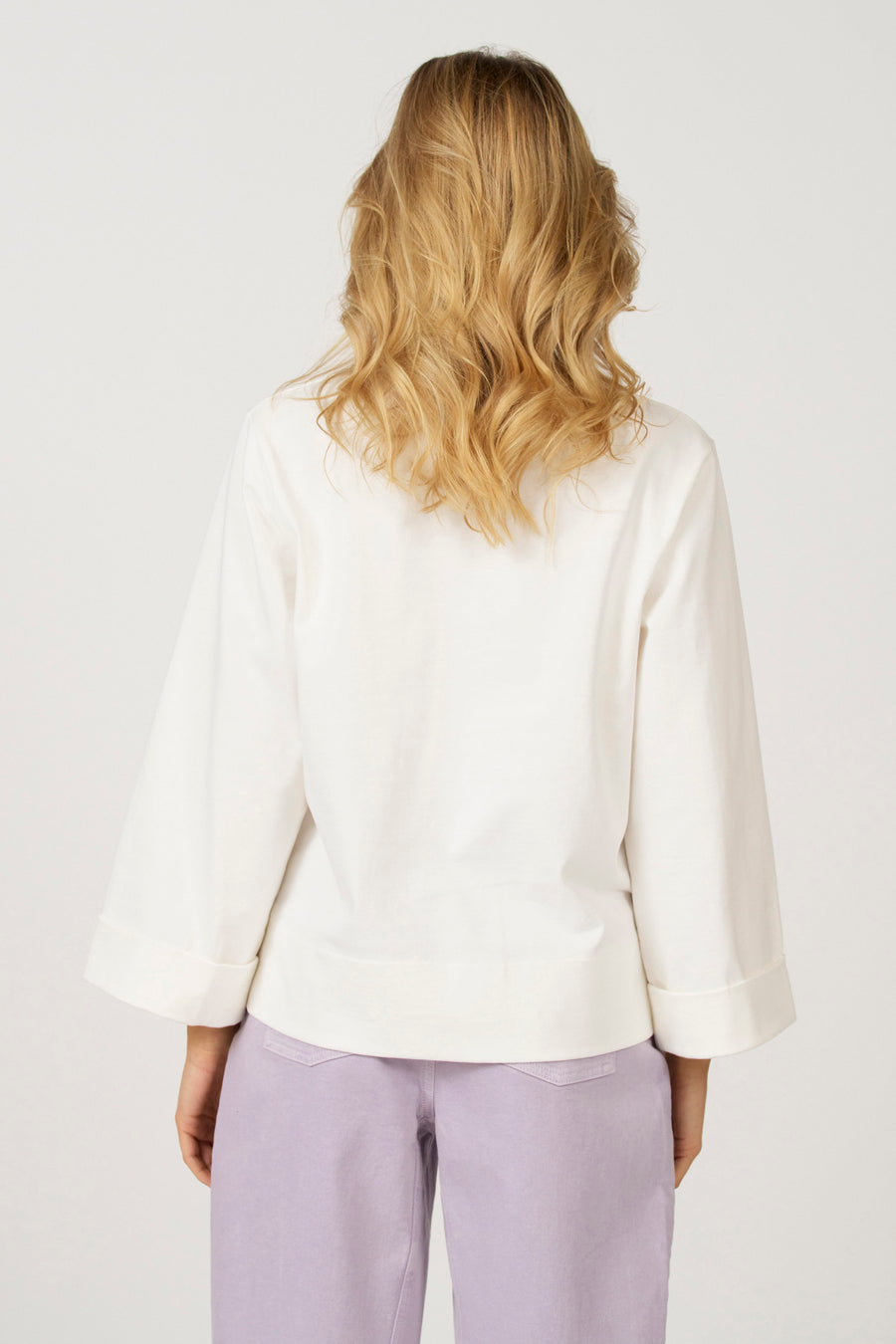 Ecru T-shirt met lange mouwen van Astrid Black Label, met wijde mouwen en een omslag, gecombineerd met een lila broek.
