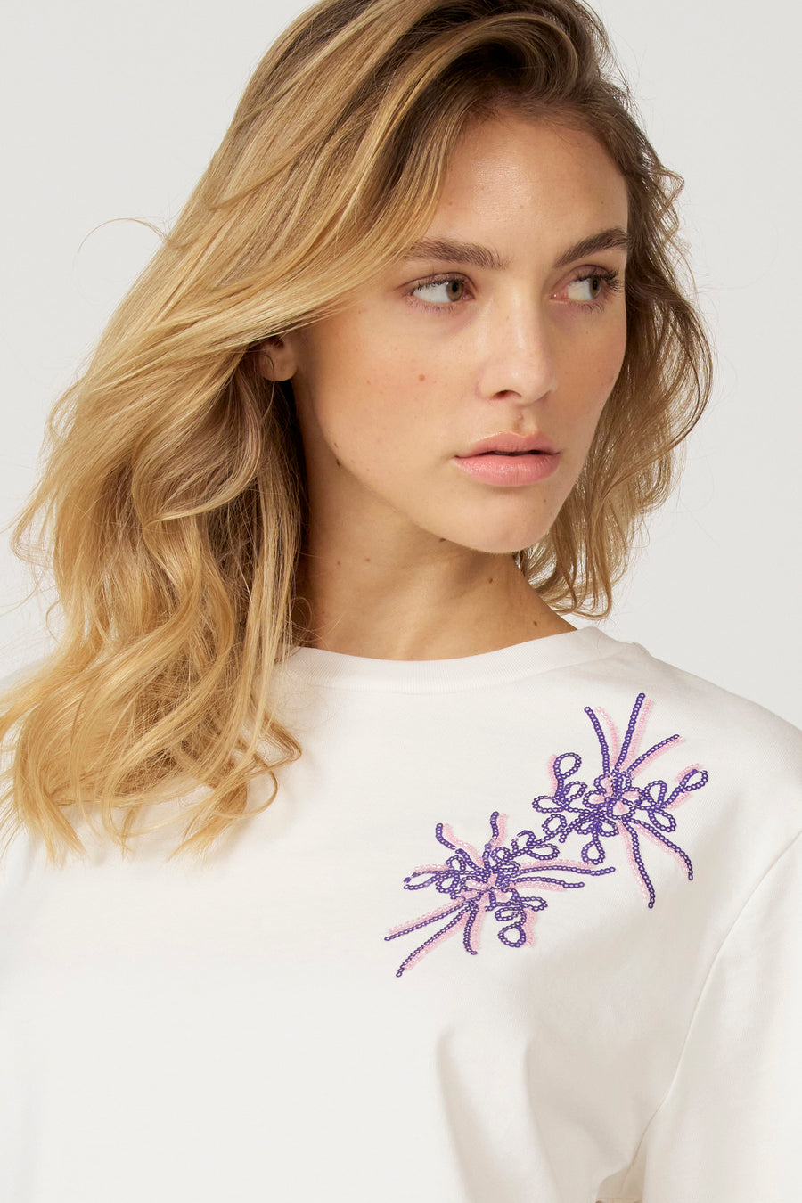 Ecru T-shirt met lange mouwen van Astrid Black Label, met bloemmotief van paarse en roze kralen.